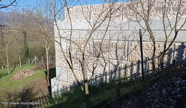 Muro di contenimento con rivestimento in pietra realizzato con blocchi modulari in calcestruzzo